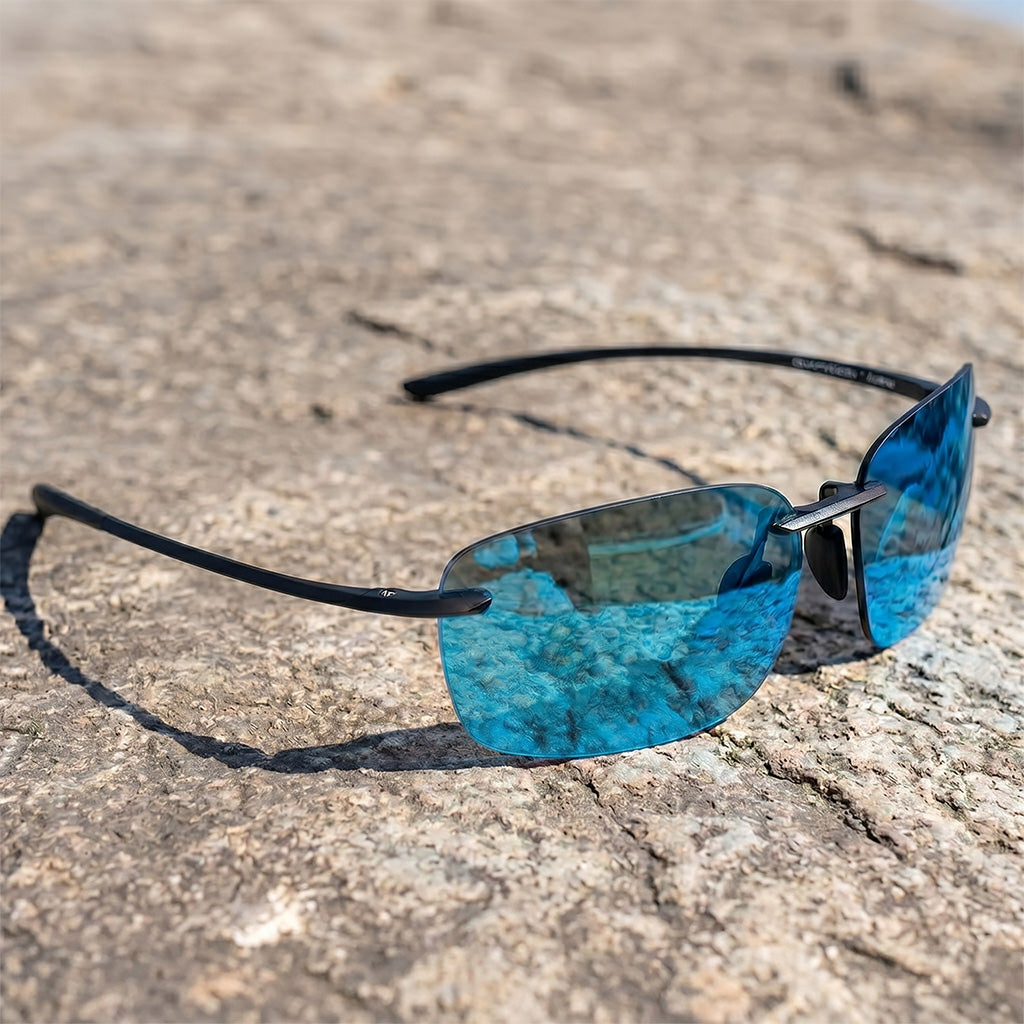 Blue sunglasses with black frame on a textured stone surface