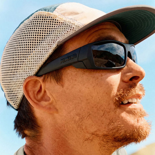 Man wearing sunglasses and a cap with a clear blue sky background